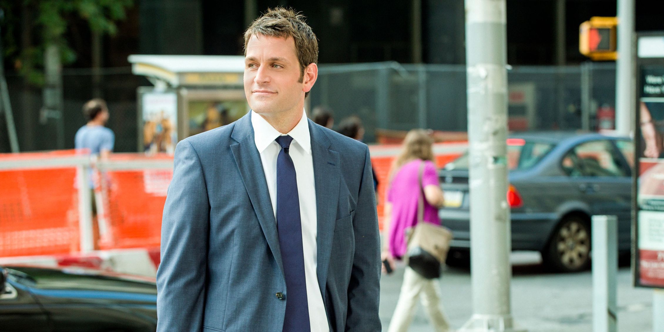 Blue Bloods Jack Boyle standing on a New York City street in a suit and tie