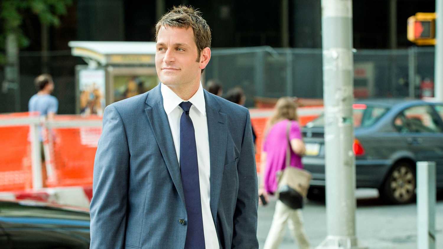 Blue Bloods Jack Boyle standing on a New York City street in a suit and tie