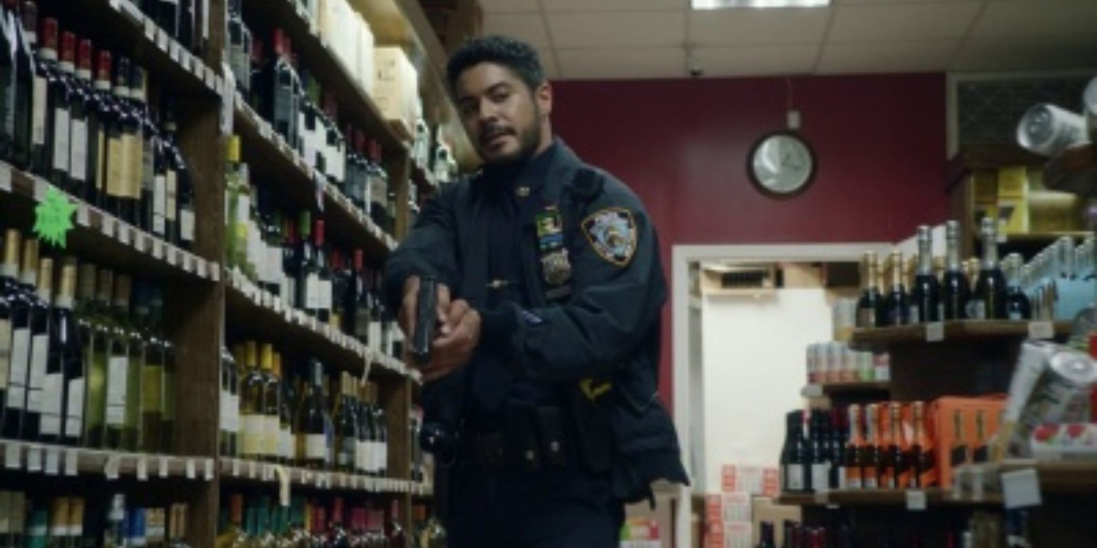 Blue Bloods Badillo tiptoeing through a liquor store aisle and holding his gun out