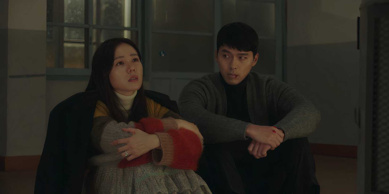 Ri Jeong-hyuk looks at Yoon Se-ri as they sit on the floor together in Crash Landing on You