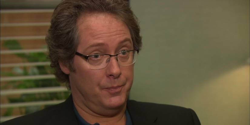 James Spader as Robert California questioning someone while sitting in the manager's office in The Office.