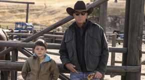 John (Kevin Costner) sand Tate (Brecken Merrill) leaning against a fence in Yellowstone.