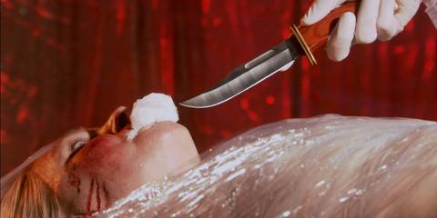 Dexter holding a knife to Nurse Mary (Denise Crosby)'s face as she's wrapped in plastic on a table in Dexter season 1, episode 3
