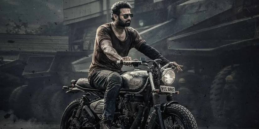 Prabhas as Salaar riding a motorcycle through a construction yard in Salaar Part 1 Ceasefire.