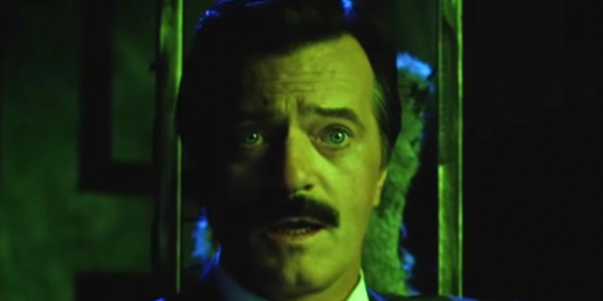 Robert Goulet as Maxie Dean looking shocked with a green glow cast on him in Beetlejuice