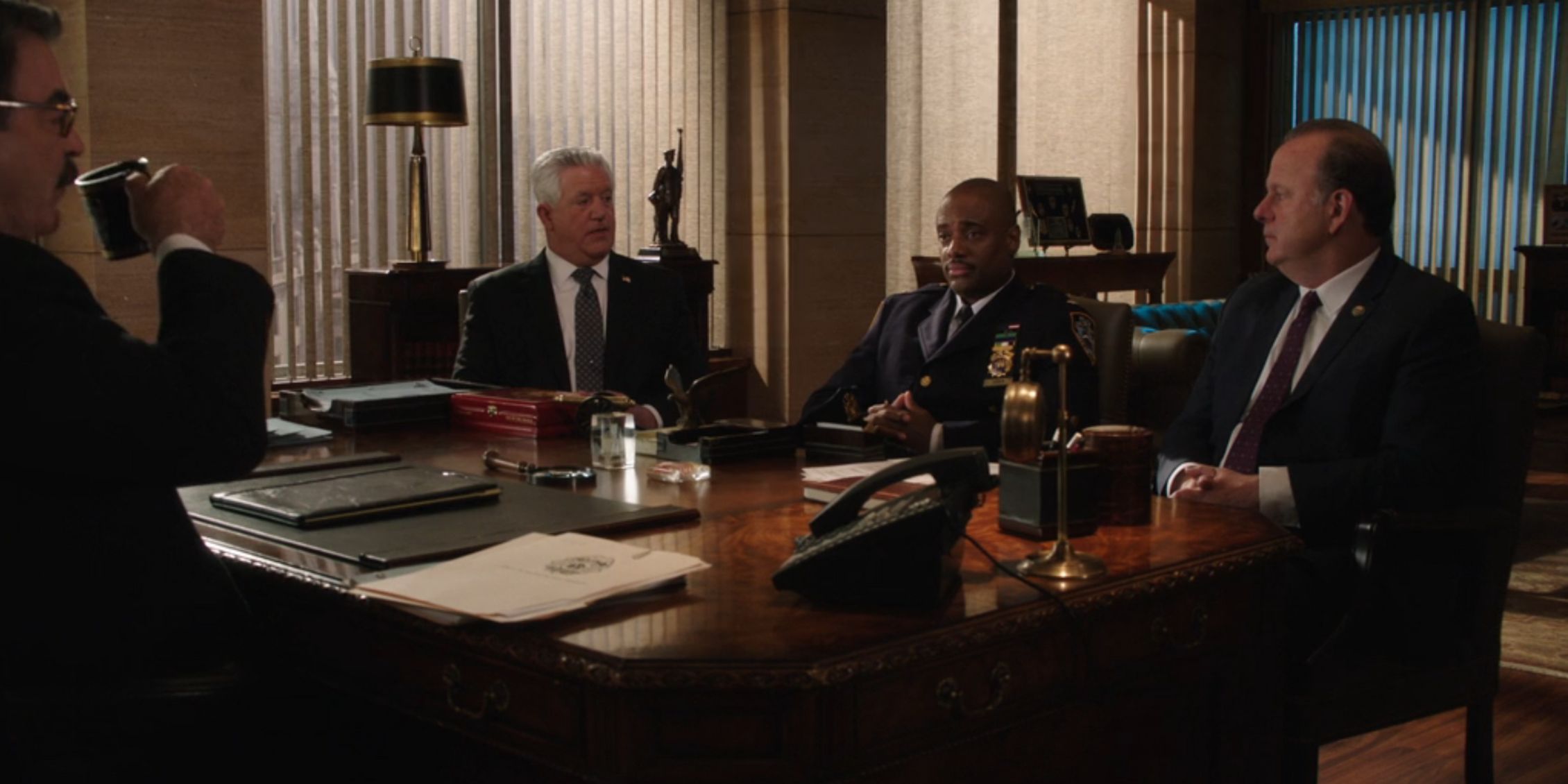 The Dream Team sitting around Frank's desk with a cop