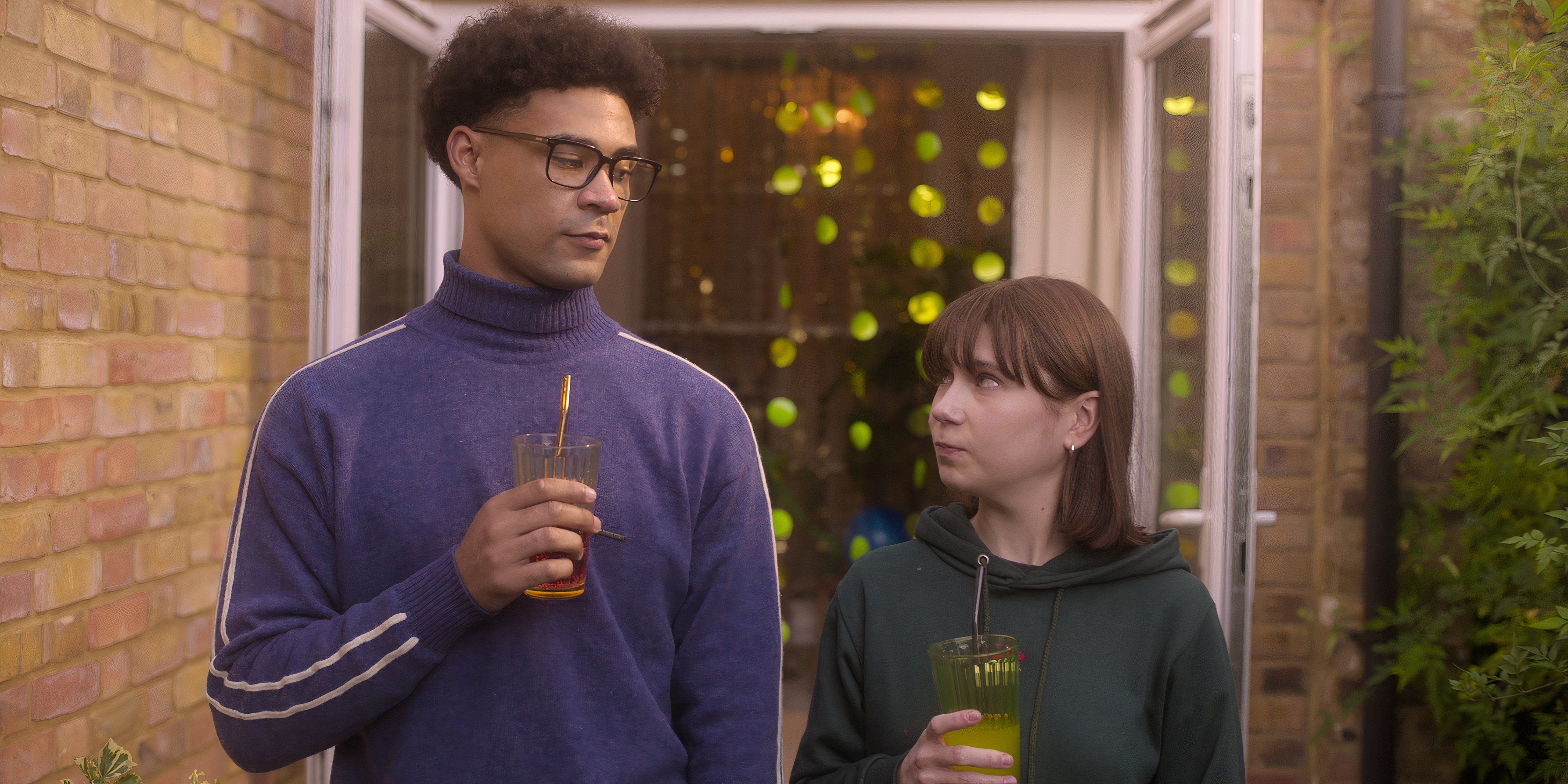 Tori (Jenny Walser) and Michael (Darragh Hand) looking at each other holding drinks in Heartstopper season 3