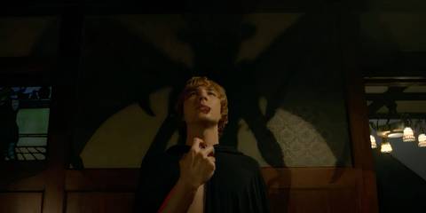 Michael eating a heart with a black shadow behind him in American Horror Story