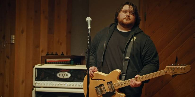 Wolfgang Van Halen holding his guitar and looking at someone in a Mammoth WVH music video.