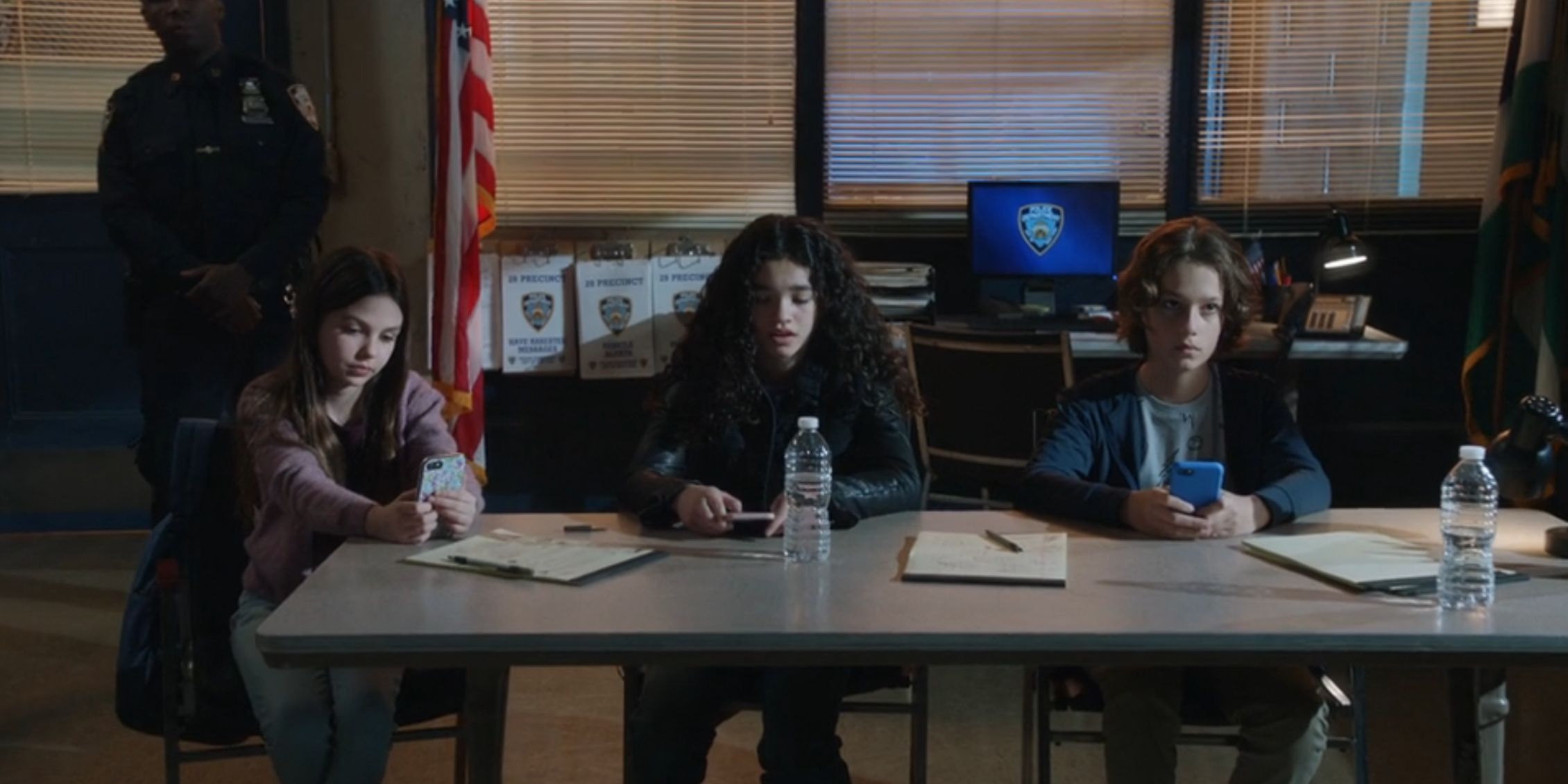 Blue Bloods two pre-teen girls and a pre-teen boy sitting at a table in an interrogation room with pads and pens in front of them