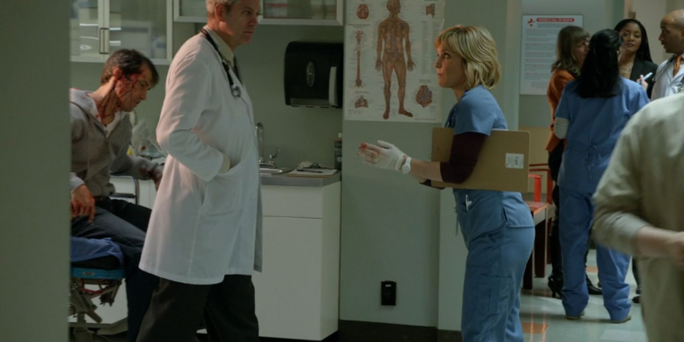 Linda wearing scrubs and bloody gloves with a clipboard under her arm