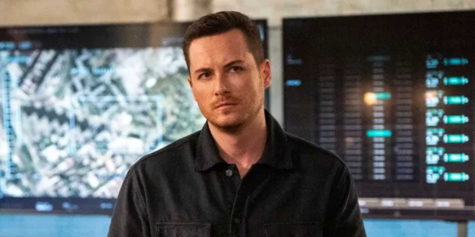 Close-up of Wes Mitchell from FBI: International standing in front of a computer screen