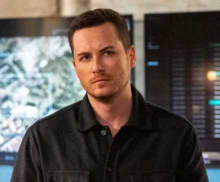 Close-up of Wes Mitchell from FBI: International standing in front of a computer screen