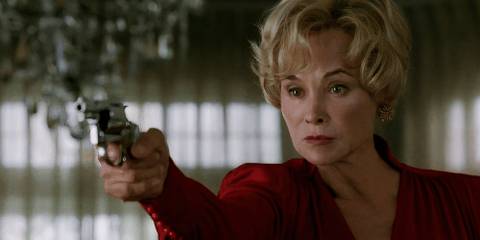 Constance in a red dress while shooting her husband and Moira in American Horror Story Murder House.