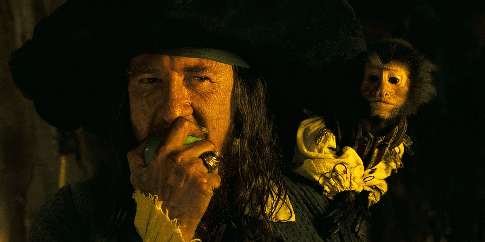 Captain Barbossa (Geoffrey Rush) biting an apple with the monkey on his shoulder at the end of Pirates of the Caribbean: Dead Man's Chest