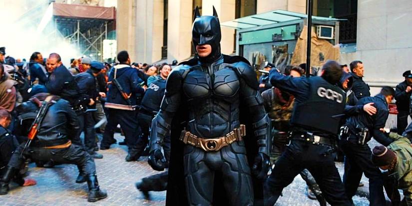 Christian Bale's Batman standing in the middle of a riot on the streets in The Dark Knight Rises
