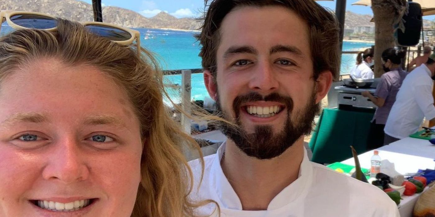 Cloyce in Below Deck Sailing Yacht smiling with a guest in his chef jacket yacht in the background