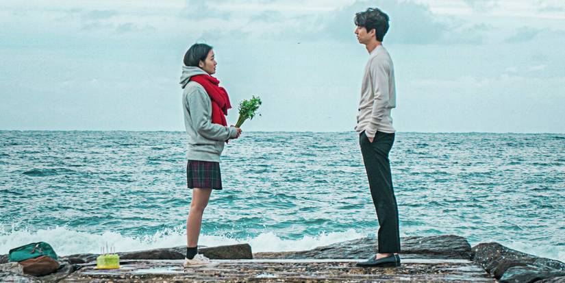 Gong Yoo standing next to the ocean facing a young woman in Goblin