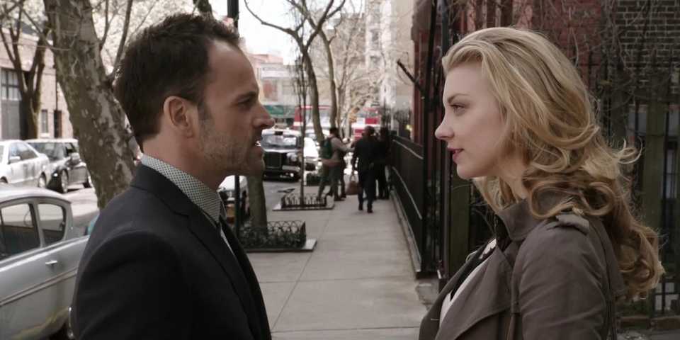 Natalie Dormer as Moriarty and Jonny Lee Miller as Sherlock Holmes looking at each other during an intense conversation on the street in Elementary.