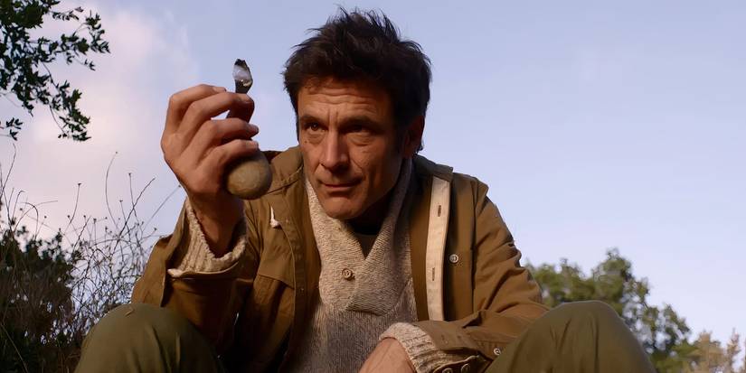 Oldman holds up something to inspect it in The Man From Earth