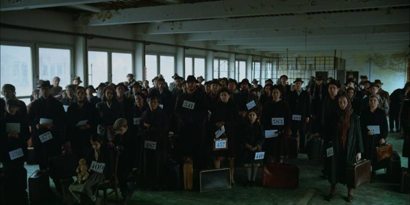 Толпа с номерами и чемоданами в фильме "Бруталист"