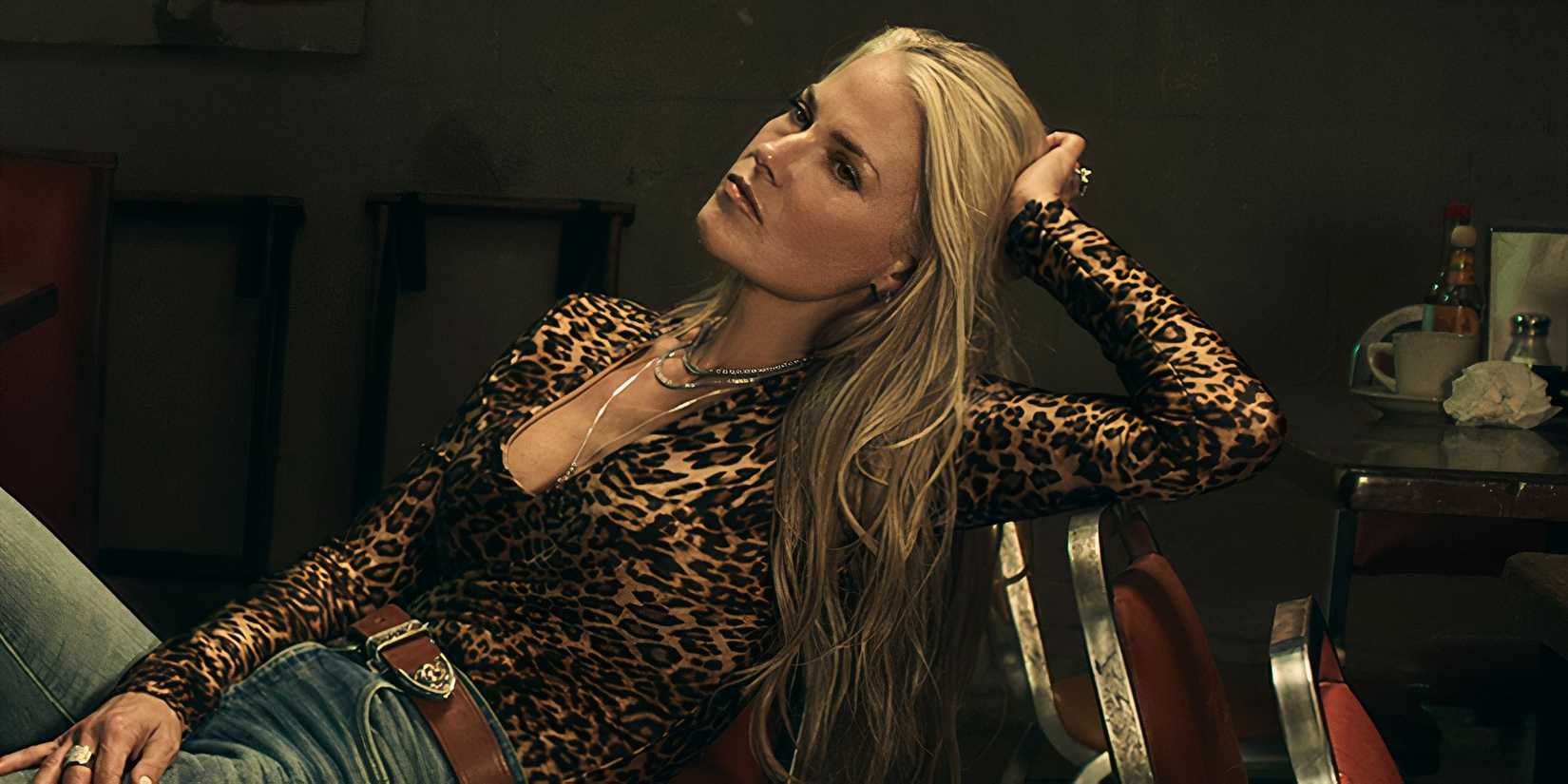 Ali Larter as Angela leaning back in a chair in Landman