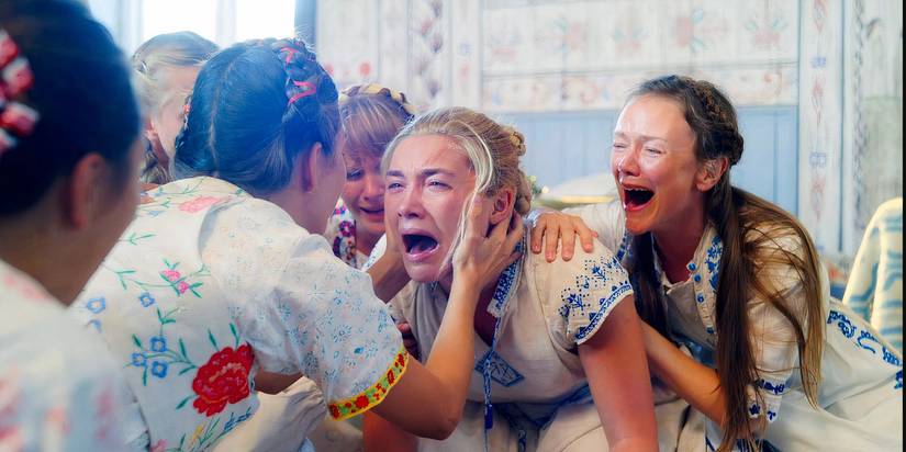Florence Pugh chorando como Dani, cercada por membros do culto em <i>Midsommar</i>.