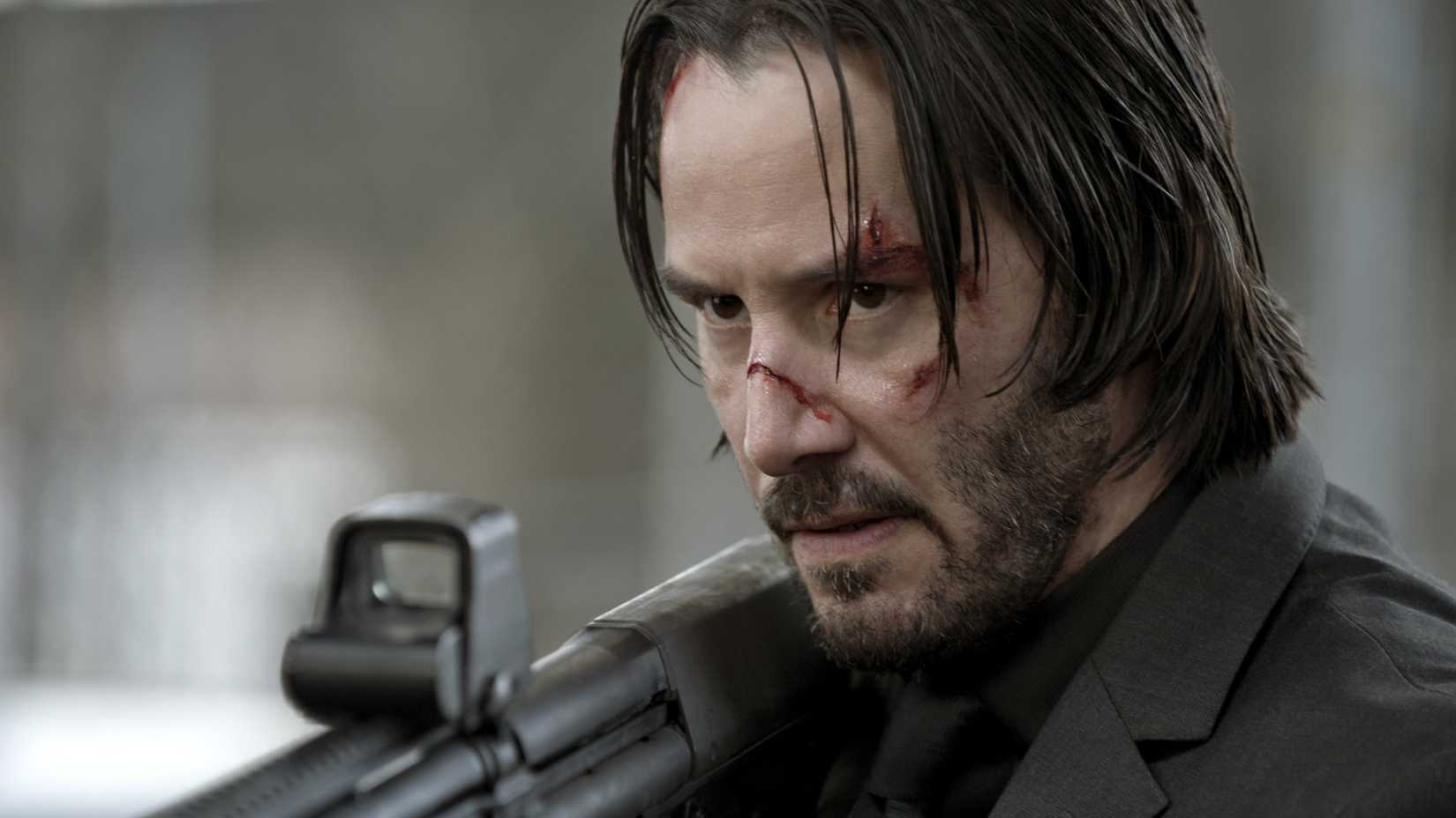 John Wick em cena de ação com espingarda no primeiro filme.