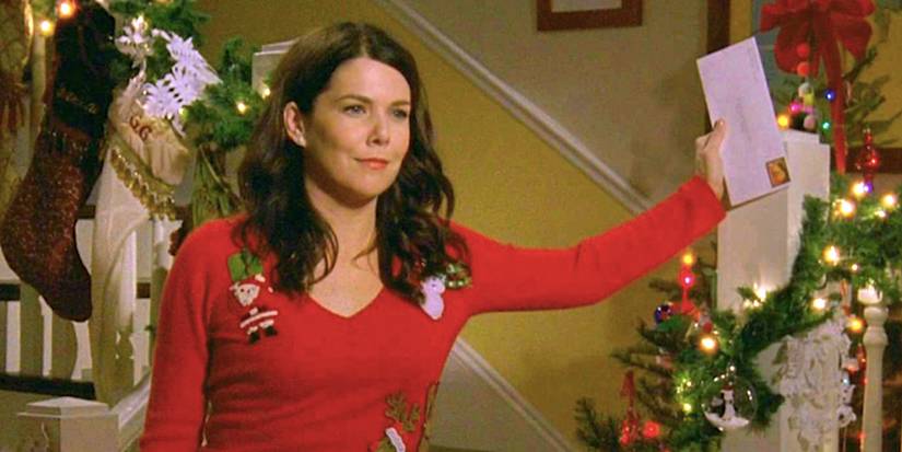 Lorelai de Lauren Graham segura uma carta para o Papai Noel enquanto está em uma escada decorada em Gilmore Girls.