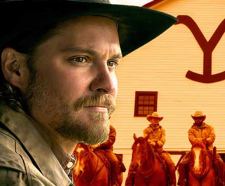 Luke Grimes' Kayce looking contently toward the cowboys in front of the bunkhouse in Yellowstone season 5