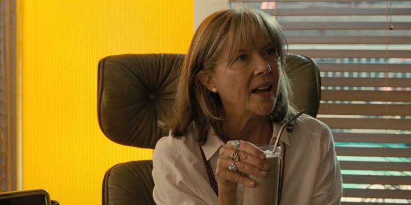 Annette Bening sitting in a chair in Poolman