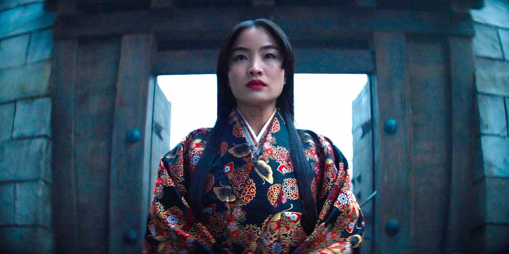 Mariko stands resolutely before a gate in a scene from Shogun season 1