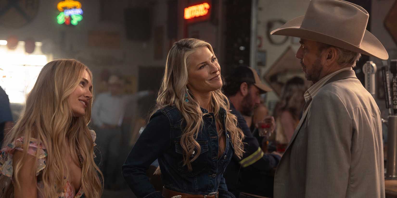 Michelle Randolph's Ainsley and Ali Larter's Rebecca smiling and standing next to Billy Bob Thornton's Tommy at a bar in Landman