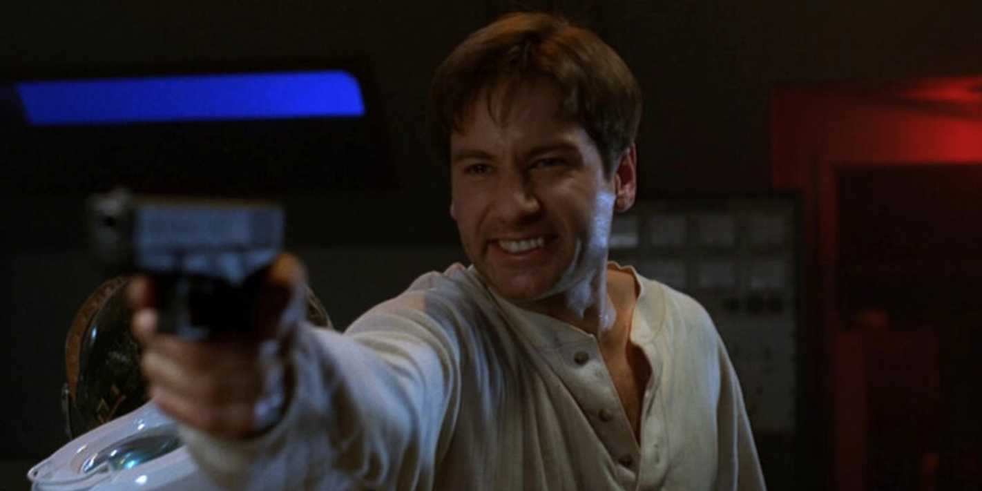 Mulder holding a gun and grinning in The X-Files