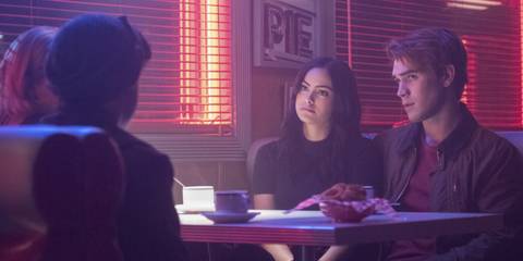 Archie and Veronica sitting in a diner booth talking to Jughead in Riverdale episode 