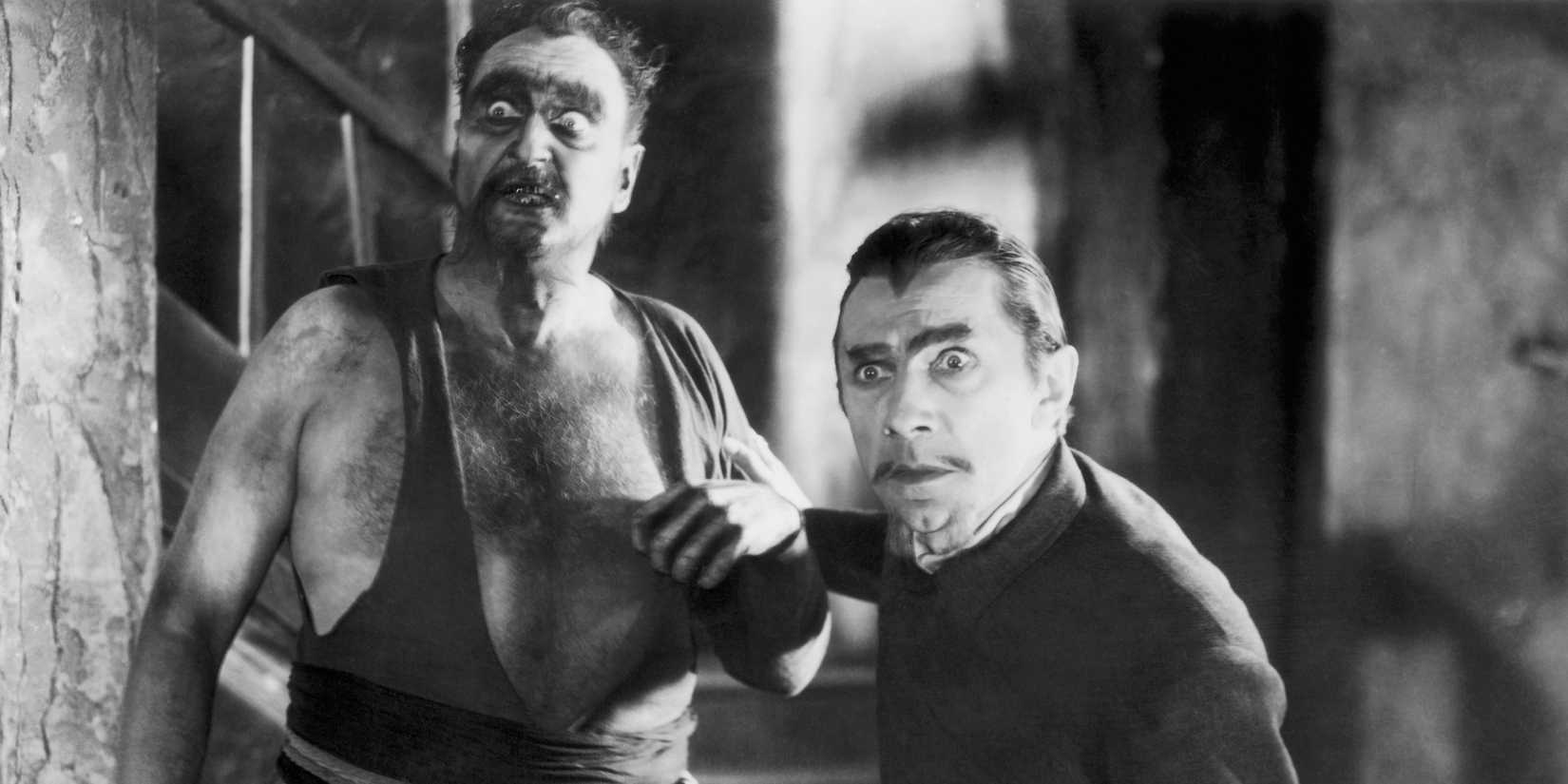 'Murder' Legendre (Bela Lugosi) and Chauvin (Frederick Peters) in White Zombie (1932). Legendre and Chauvin both have looks of horror on their faces, and Legendre clutches at Chauvin's arm.