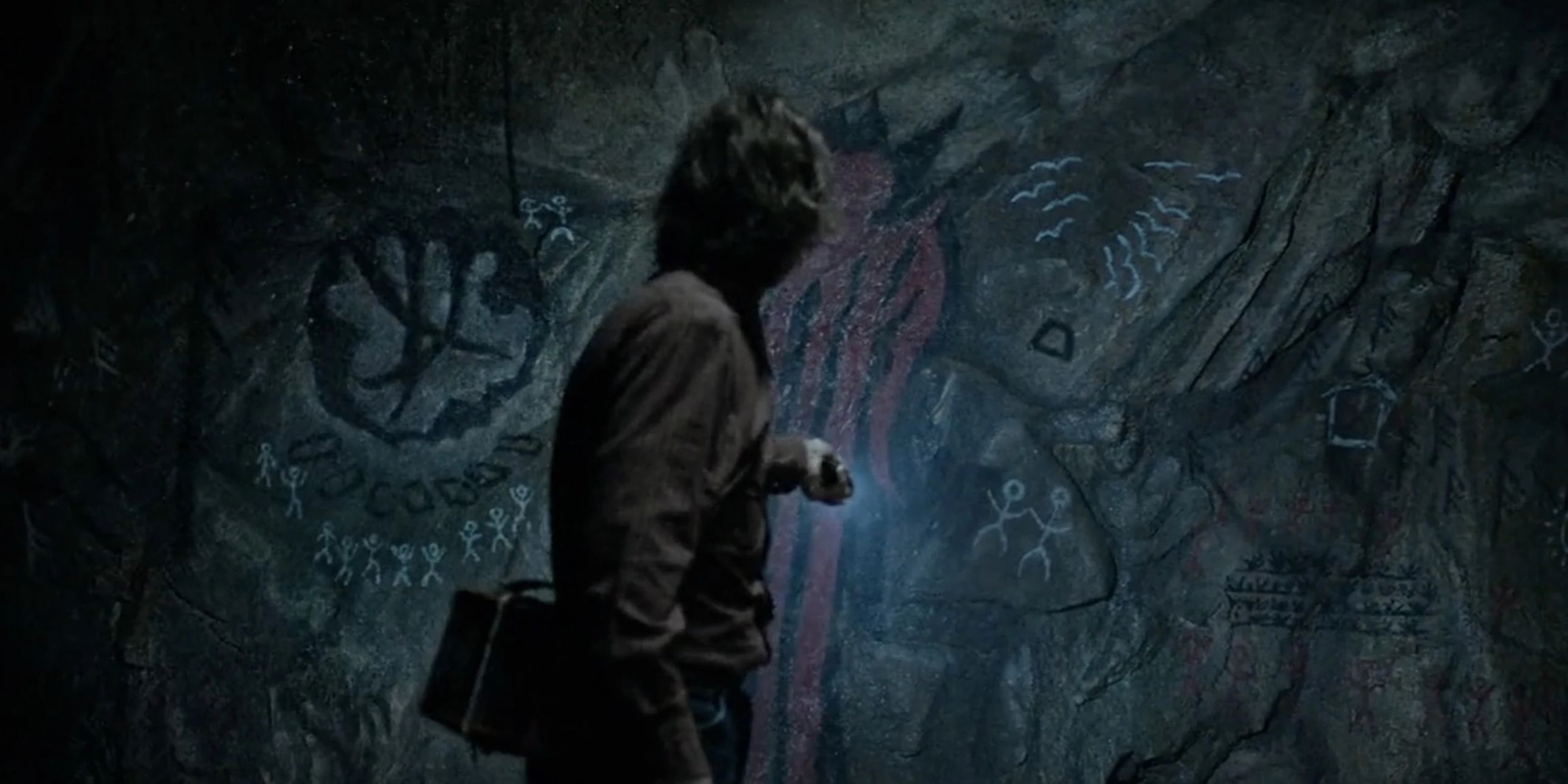 Victor (Scott McCord) shining a light on the tunnel drawings in From