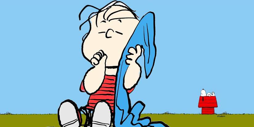 Peanuts: Linus with his blanket with Snoopy behind him lying on his doghouse looking up at a blue sky.