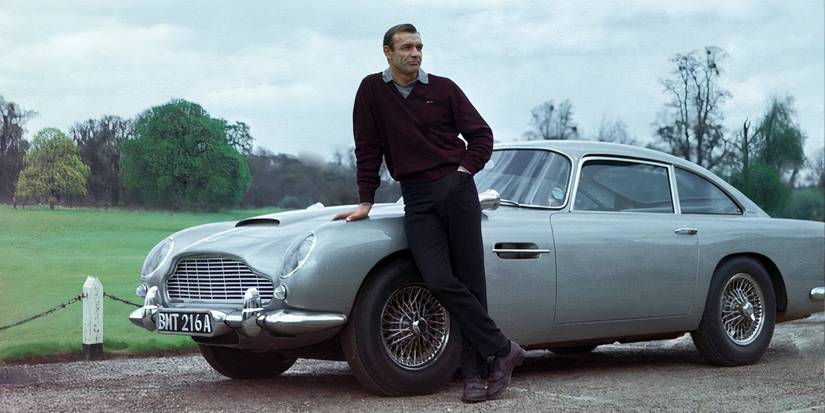 Sean Connery leaning against his James Bond car outside.