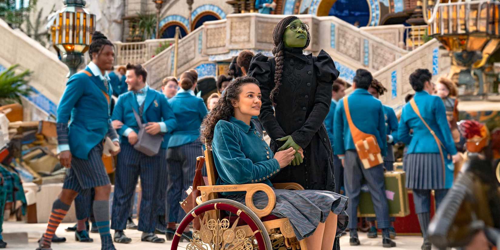 Nessarose (Marissa Bode) and Elphaba (Cynthia Erivo) holding hands and looking around nervously while arriving at Shiz University in Wicked.