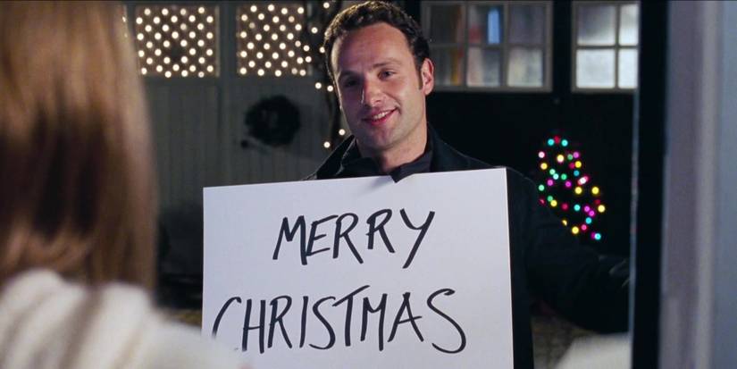 Andrew Lincoln holding a sign that says Merry Christmas in Love Actually