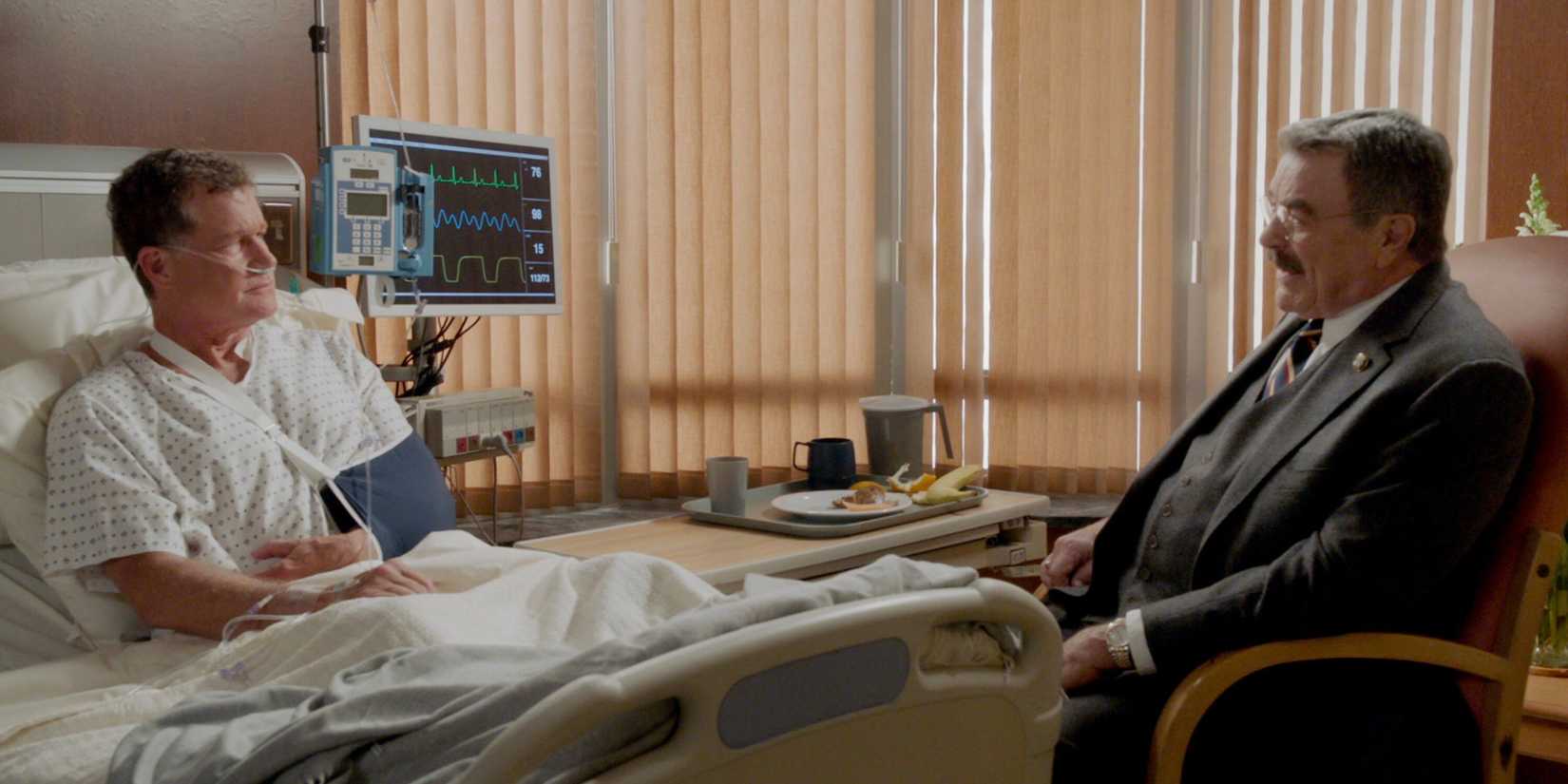 Blue Bloods Frank sitting by Mayor Chase's hospital bed while Chase wears an oxygen mask and a sling on his arm
