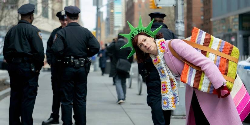 Carrie Preston in Elsbeth leaning over while wearing a styrofoam Lady Liberty headpiece