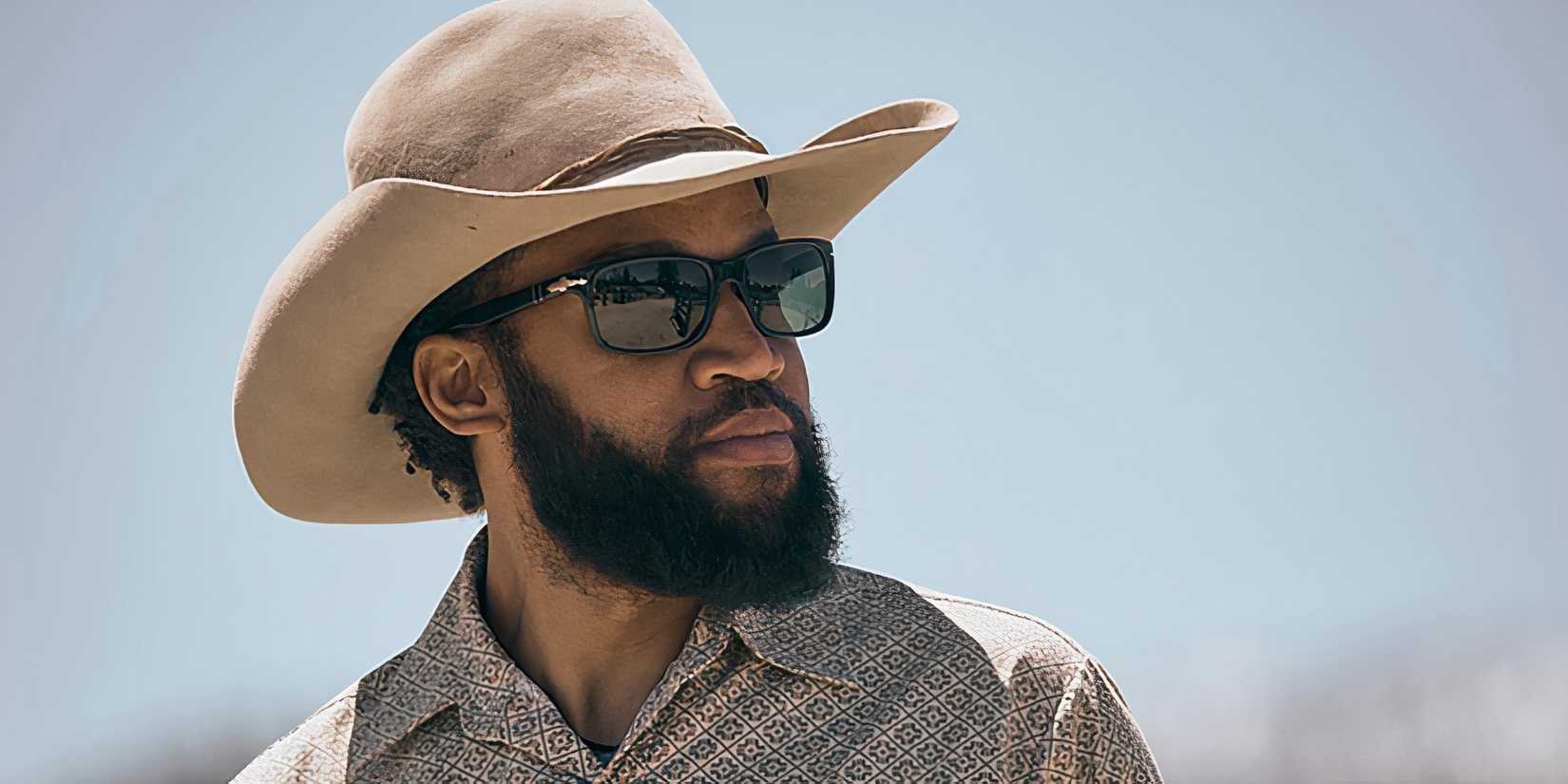 Denim Richards as Colby looking into the distance in his sunglasses and cowboy hat in Yellowstone season 5 part B
