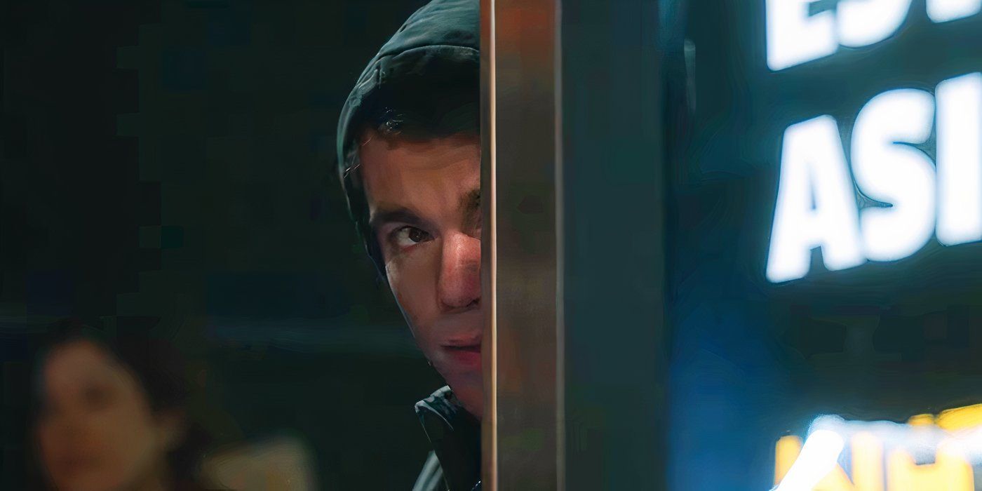 Gabriel Basso as Peter Sutherland wearing a hoodie and hiding behind a bus stop in The Night Agent season 2