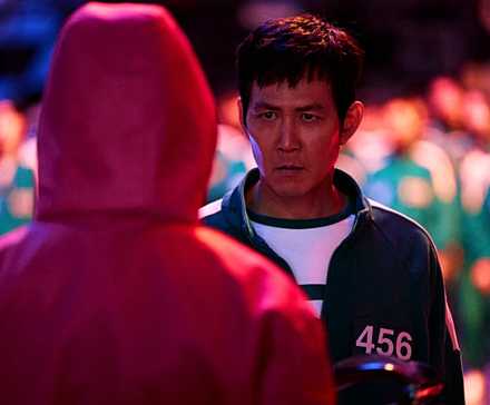 Ги-Хун смотрит прямо на охранника "Squid Game", когда мы видим охранника в своем розовом костюме сзади в 2-м сезоне "Squid Game"