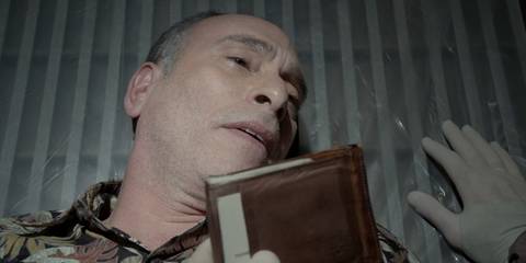 Hector Estrada (Nestor Serrano) on a kill table looking at his wallet in Dexter season 7, episode 11