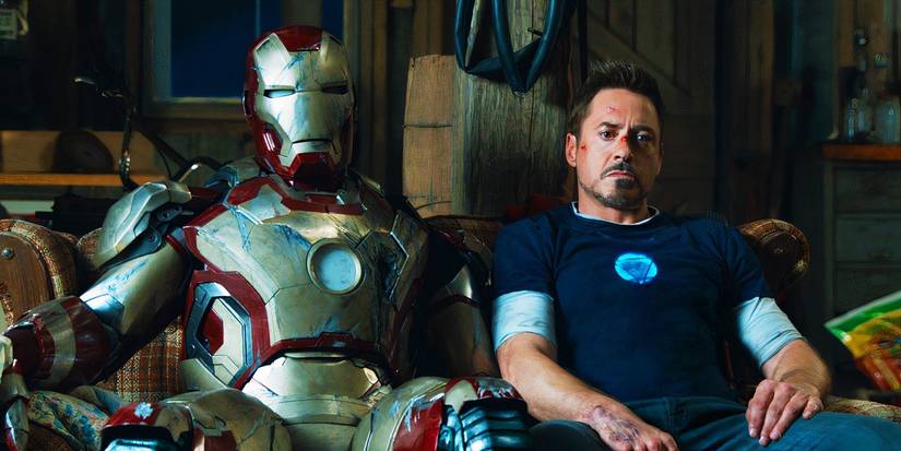 Tony Stark reclinado com a armadura do Homem de Ferro em Homem de Ferro 3