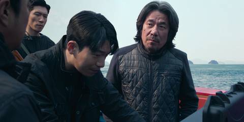 Captain Park and Jun-ho on a boat with other men in Squid Game