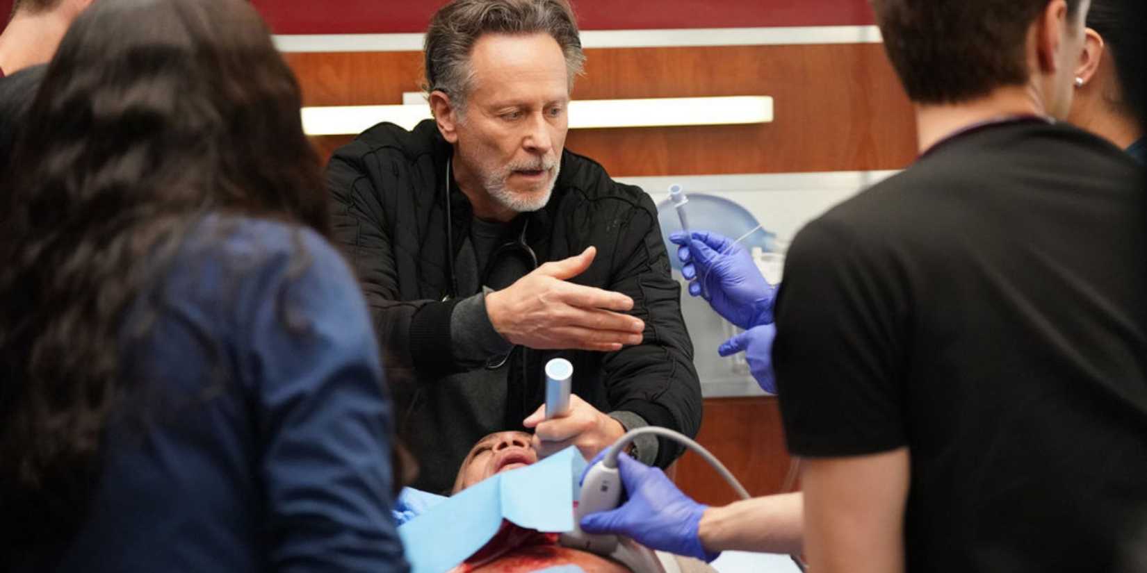 Chicago Med Archer holding his hand out for a syringe while holding equipment over Goodwin with his other hand